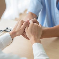 Hand of female doctor holding on her senior patient - selective focus point